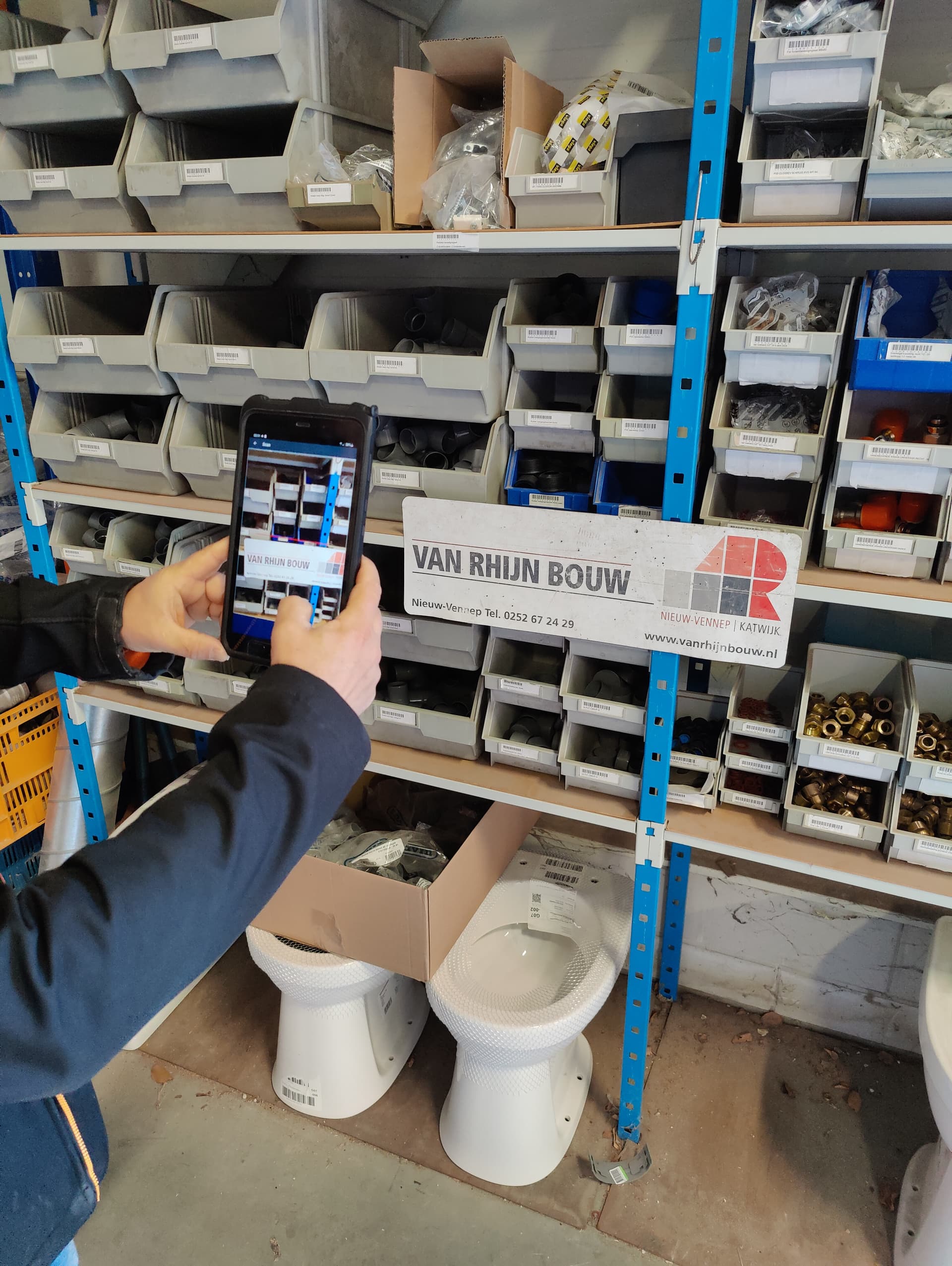 Medewerker scant barcodes met de ScanWerkApp op een telefoon bij Van Rhijn Bouw